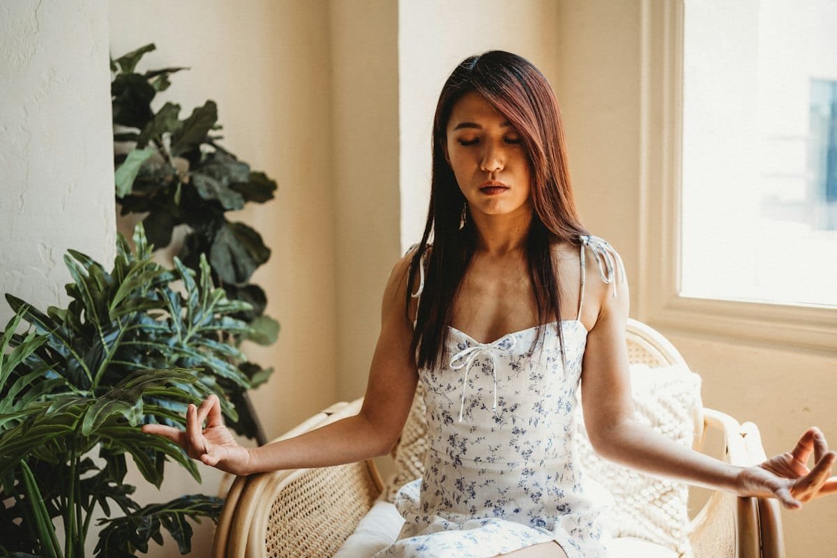 Woman seated with arms raised, releasing tension to stop overthinking